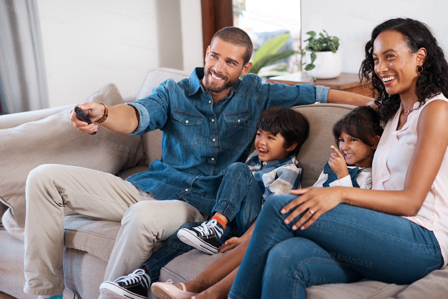 Buy stock photo Shot of a couple watching something on the television with their two young kids