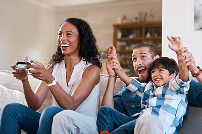 Buy stock photo Shot of a woman playing video games while relaxing at home with her husband and son