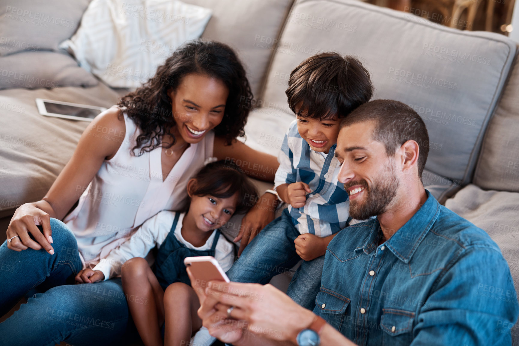Buy stock photo Shot of a family of four watching something on a cellphone