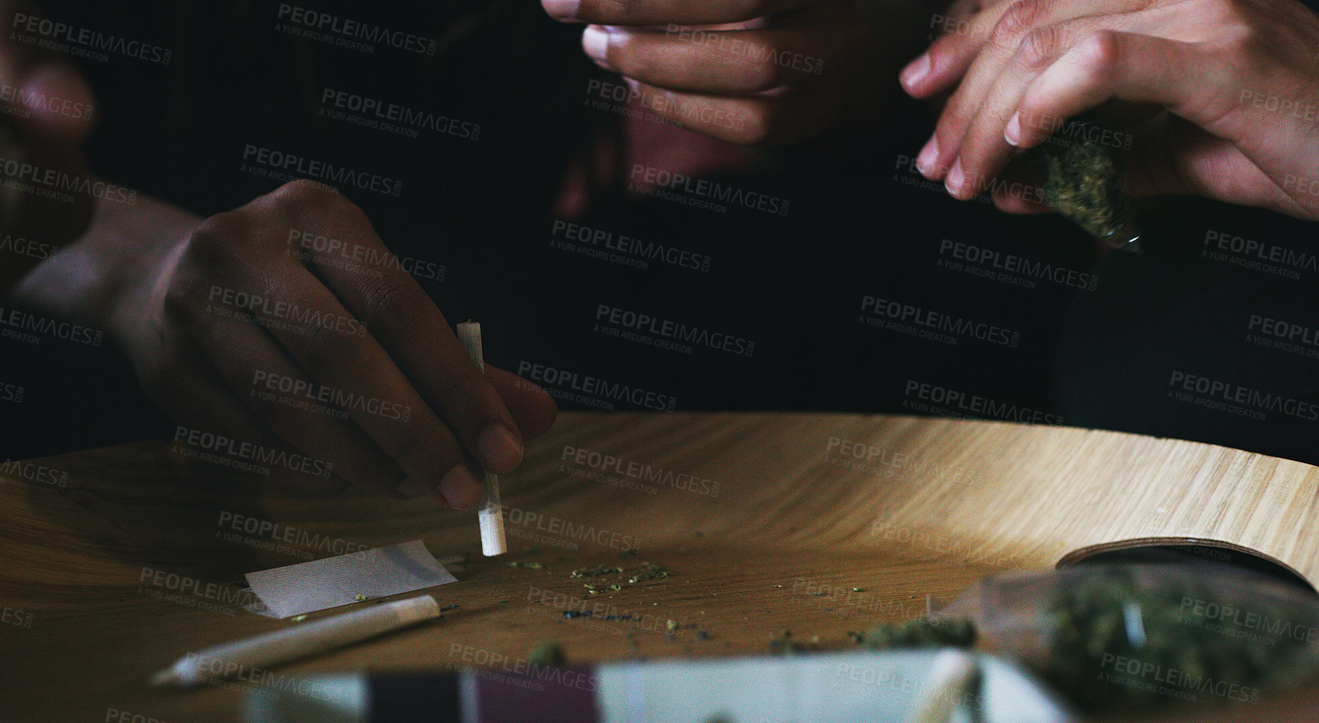 Buy stock photo Cropped shot of men rolling a marijuana joint at home