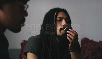 Buy stock photo Shot of two young men smoking a marijuana joint at home