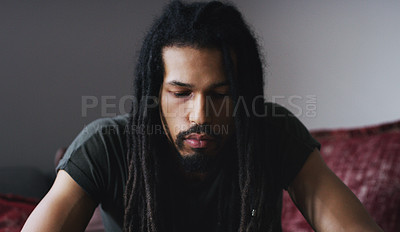 Buy stock photo Shot of a young man sitting on the sofa and looking depressed