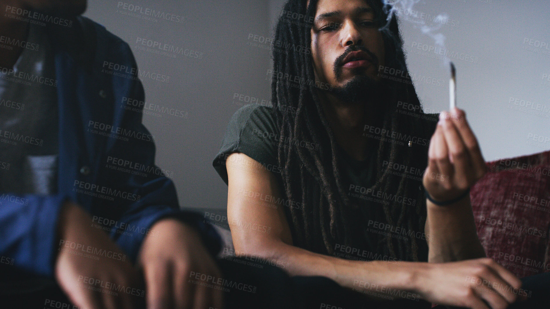 Buy stock photo Shot of two young men smoking a marijuana joint at home