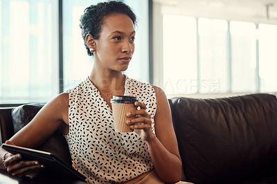 Buy stock photo Shot of a young businesswoman drinking coffee and using a digital tablet while sitting on a couch in her office