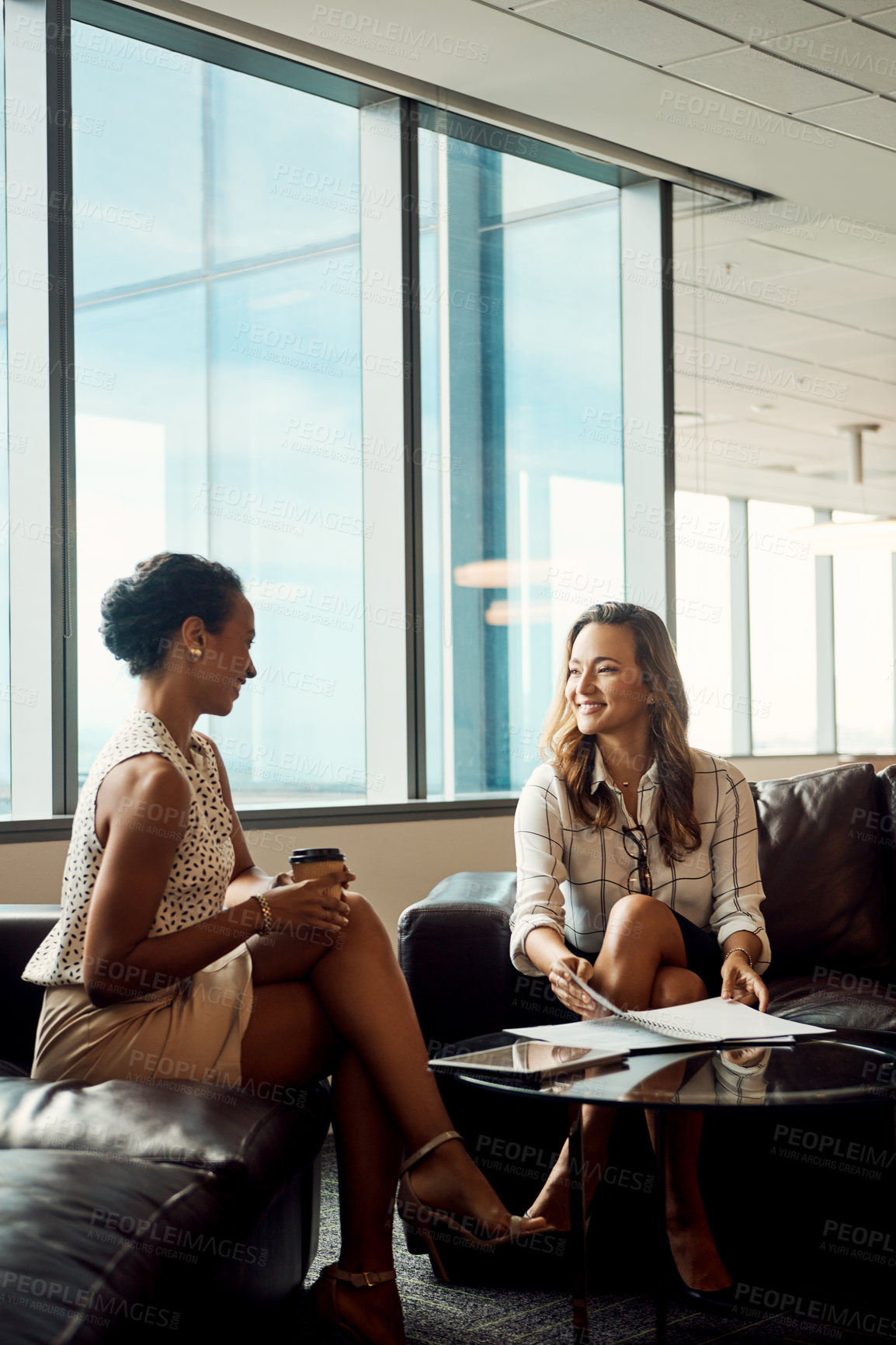 Buy stock photo Full length shot of two young businesswomen going over some paperwork together in their office