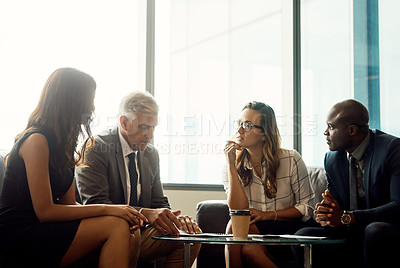 Buy stock photo Shot of a group of businesspeople going over paperwork during a meeting in an office