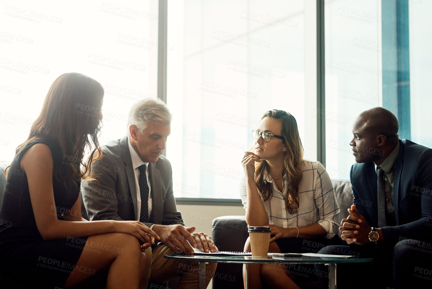 Buy stock photo Shot of a group of businesspeople going over paperwork during a meeting in an office