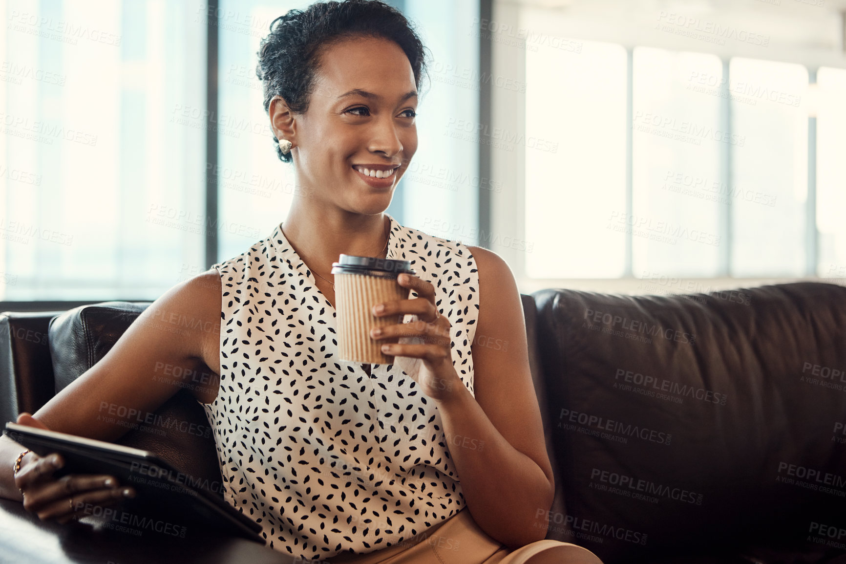 Buy stock photo Shot of a young businesswoman drinking coffee and using a digital tablet while sitting on a couch in her office