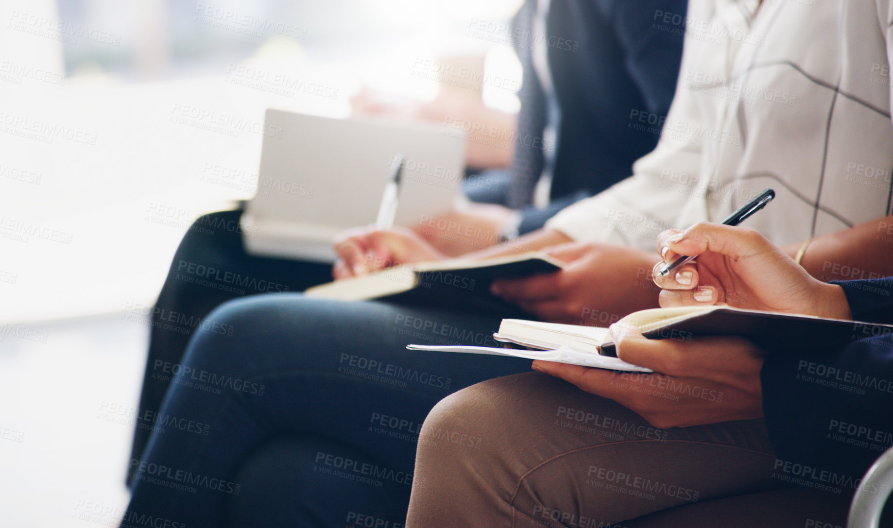 Buy stock photo Cropped shot of unrecognizable businesspeople sitting and writing notes in a book while in the office during the day