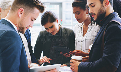Buy stock photo Cropped shot of a diverse group of businesspeople standing and using technology while in the office during the day