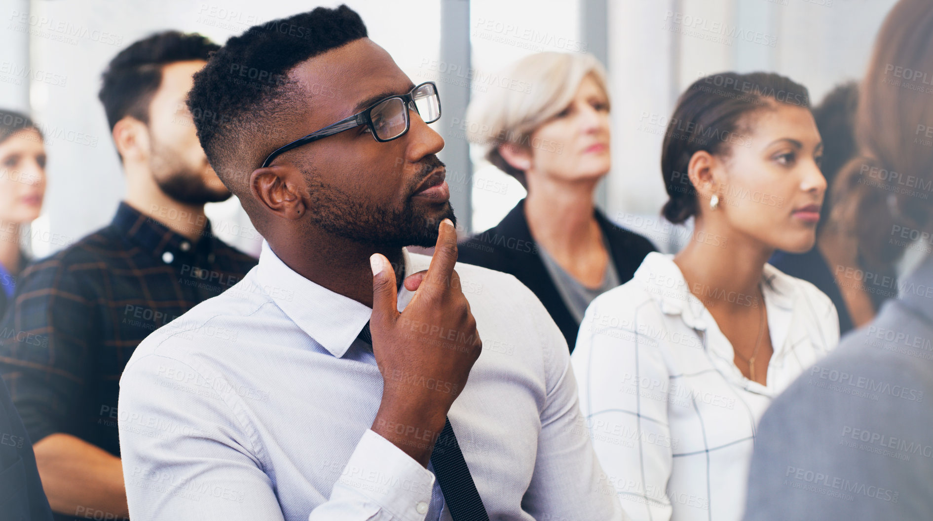 Buy stock photo Cropped shot of a handsome young businessman sitting with his colleagues while in the office during the day