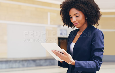 Buy stock photo Cropped shot of an attractive young businesswoman standing alone and using a tablet while in the office during the day