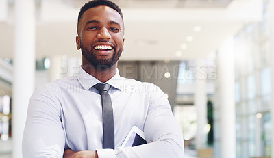 Buy stock photo Cropped portrait of a handsome young businessman standing with his arms folded ad holding a tablet while in the office
