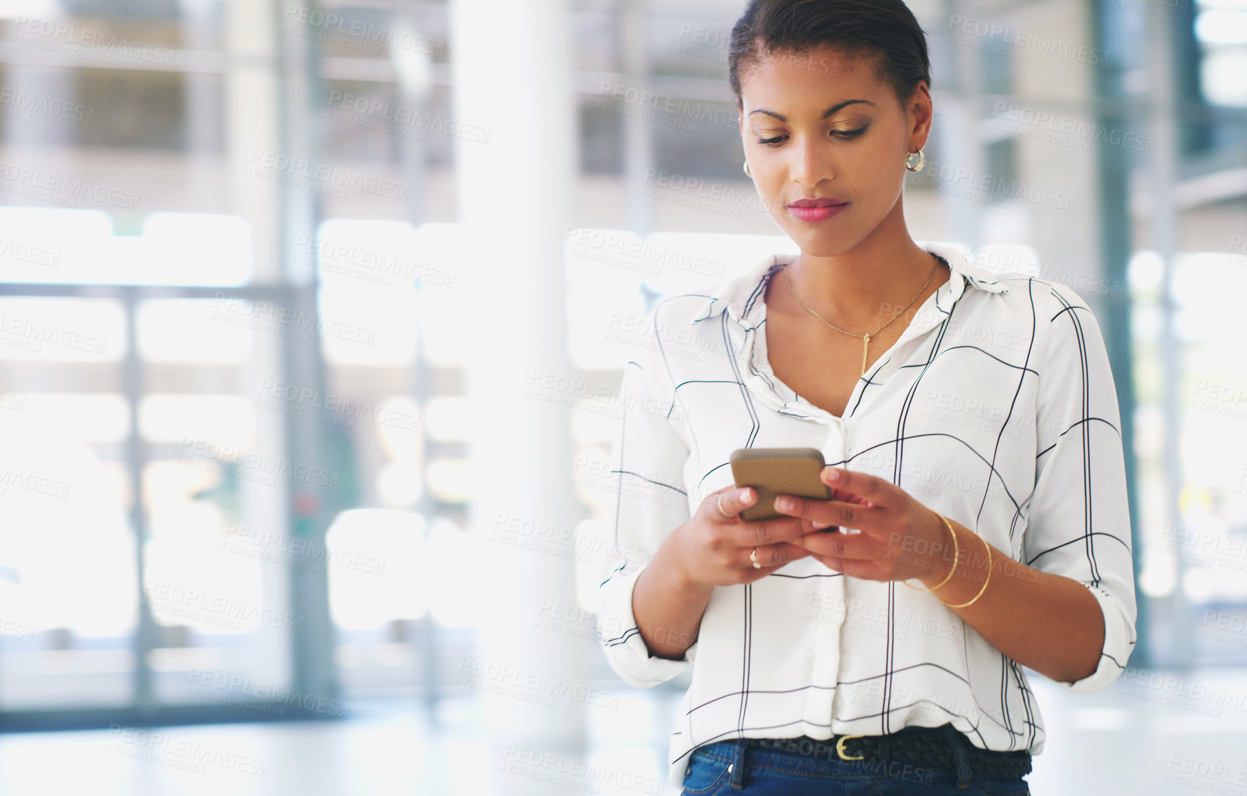 Buy stock photo Cropped shot of an attractive young businesswoman standing alone and using a cellphone while in the office during the day