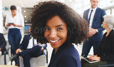Buy stock photo Cropped portrait of an attractive young businesswoman sitting and smiling while her colleagues work behind her in the office