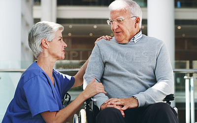 Buy stock photo Cropped shot of a senior man sitting in a wheelchair while his attractive mature nurse aid assists him indoors