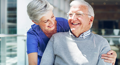 Buy stock photo Cropped shot of a happy senior man sitting in a wheelchair while his attractive mature nurse aid assists him indoors