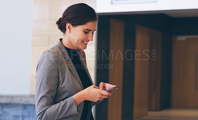 Buy stock photo Cropped shot of an attractive young businesswoman standing alone and using a cellphone while in the office during the day