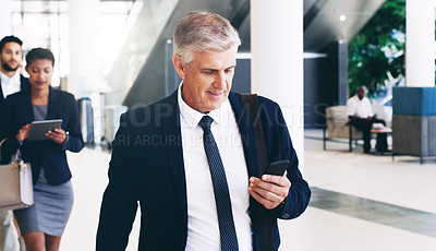 Buy stock photo Phone, senior and businessman walking to meeting, conference or workshop, texting and in office building. Corporate, boss and employee team check schedule, appointment and planning before tradeshow