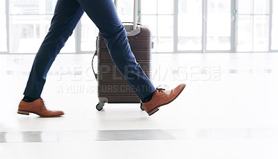Buy stock photo Cropped shot of an unrecognizable businessman walking and pulling a suitcase while in the office during the day