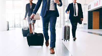 Buy stock photo Cropped shot of three unrecognizable businesspeople walking and pulling suitcases while in the office during the day