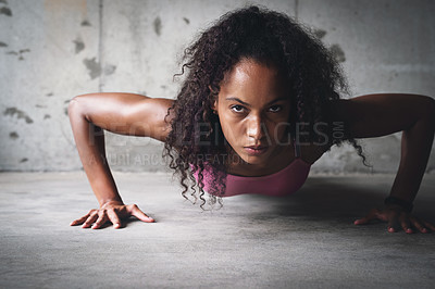 Buy stock photo Portrait of an attractive young sportswoman doing push ups while exercising inside a parking lot