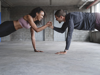 Buy stock photo Shot of a sporty young couple holding hands while exercising together inside an underground parking lot