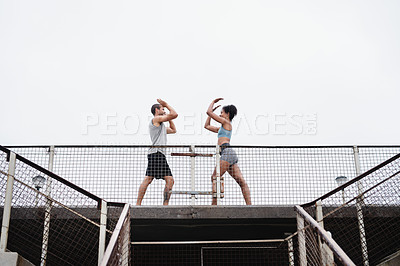 Buy stock photo Full length shot of a sporty young couple joining for a high five while exercising outdoors