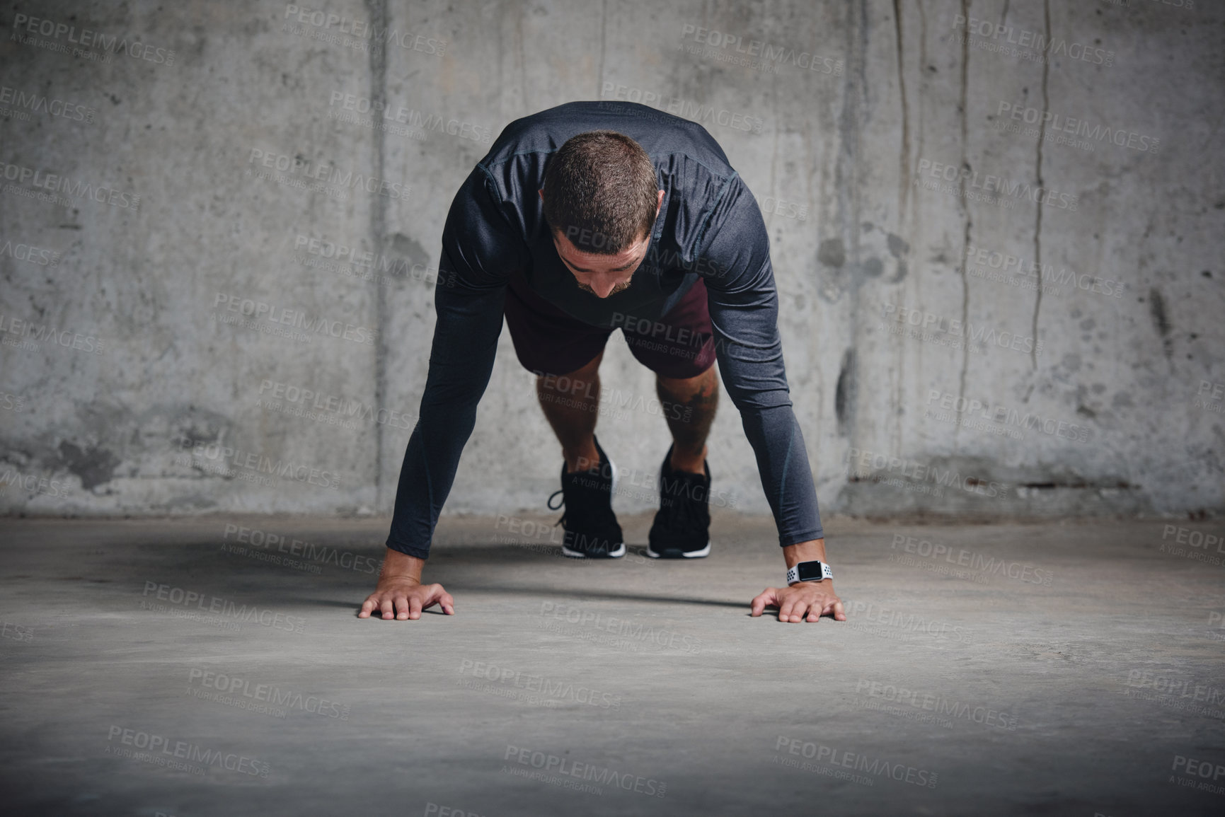 Buy stock photo Shot of a handsome young sportsman doing push ups while exercising inside a parking lot