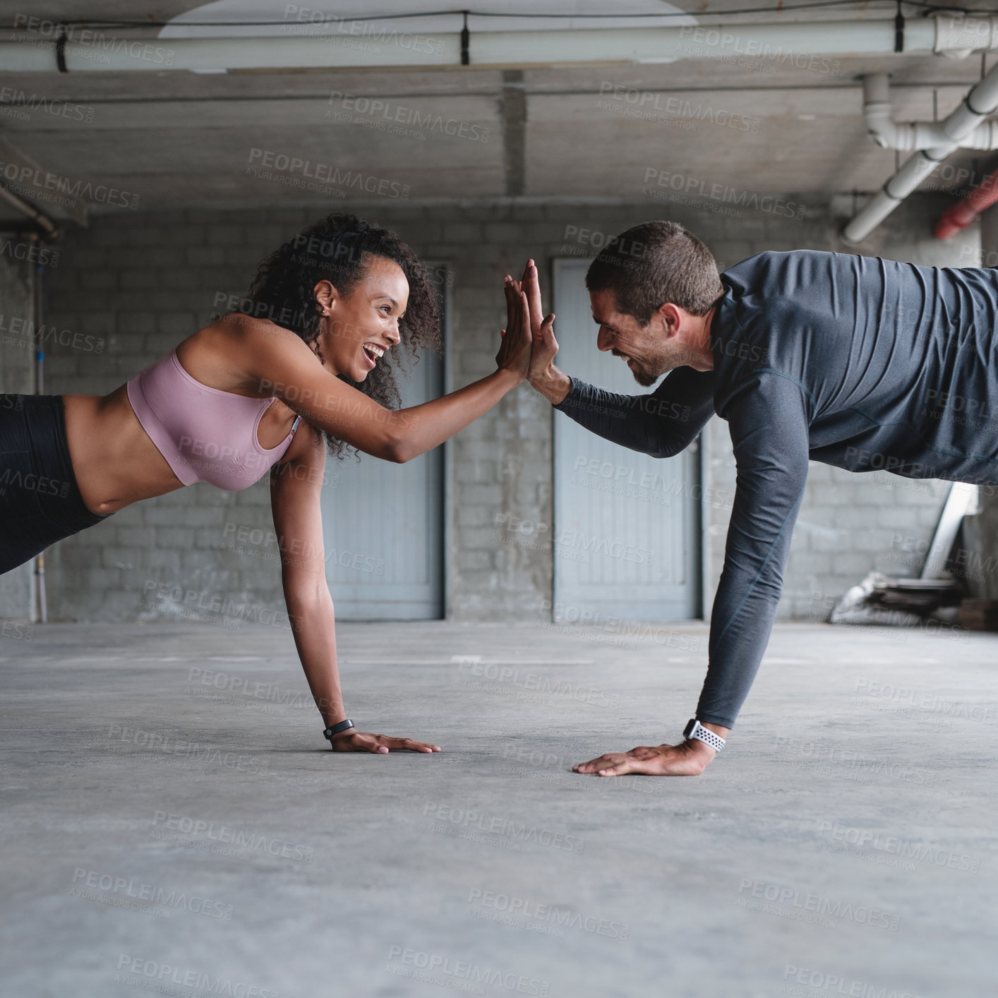 Buy stock photo Shot of a sporty young couple exercising together inside an underground parking lot