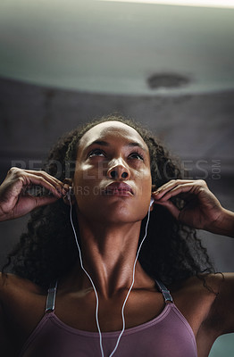 Buy stock photo Shot of an attractive young sportswoman listening to music while exercising indoors