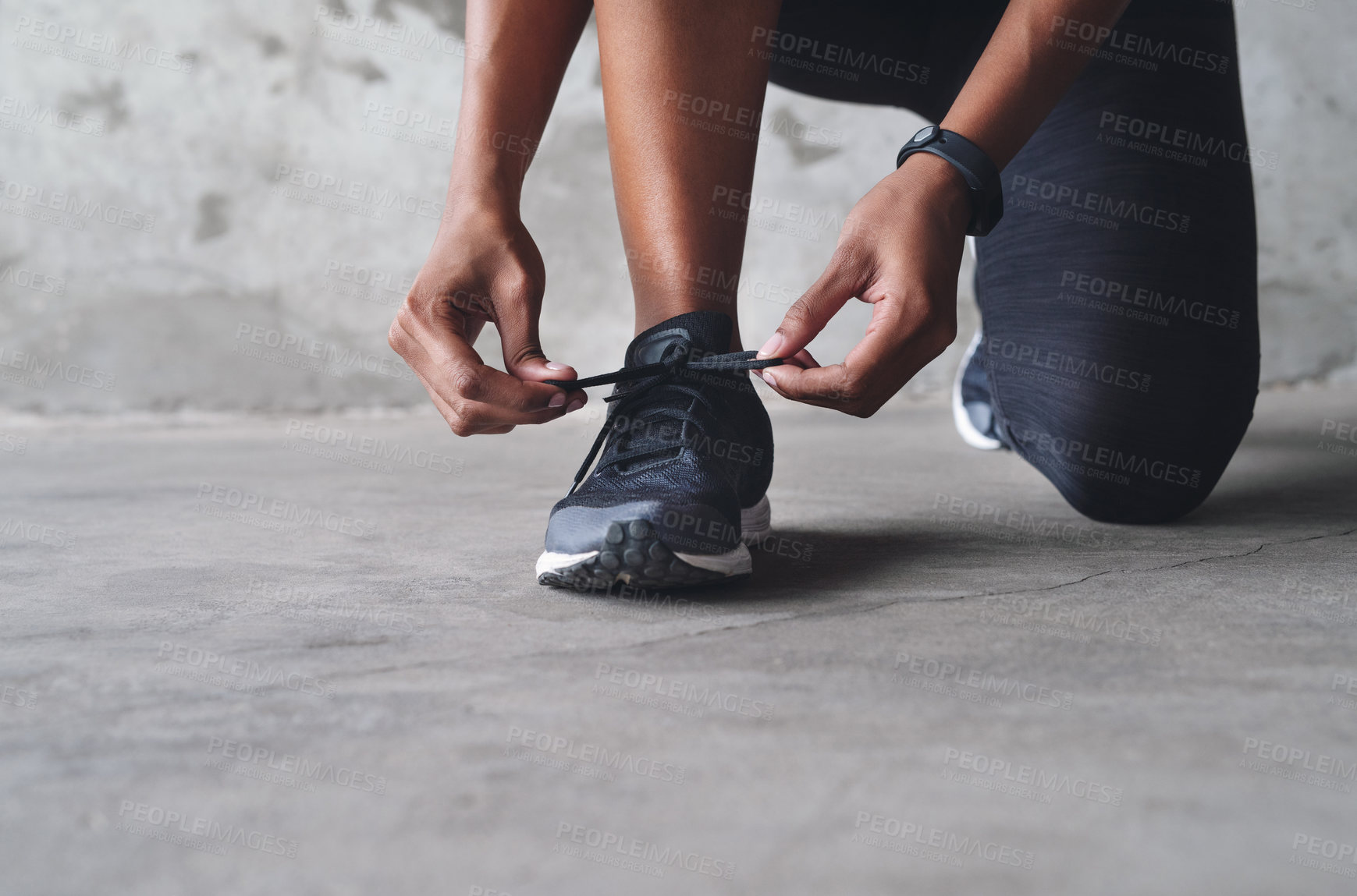 Buy stock photo Shot of an unrecognizable sportswoman tying her shoelaces while exercising indoors