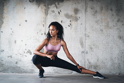 Buy stock photo Full length shot of an attractive young sportswoman stretching while exercising inside a parking lot