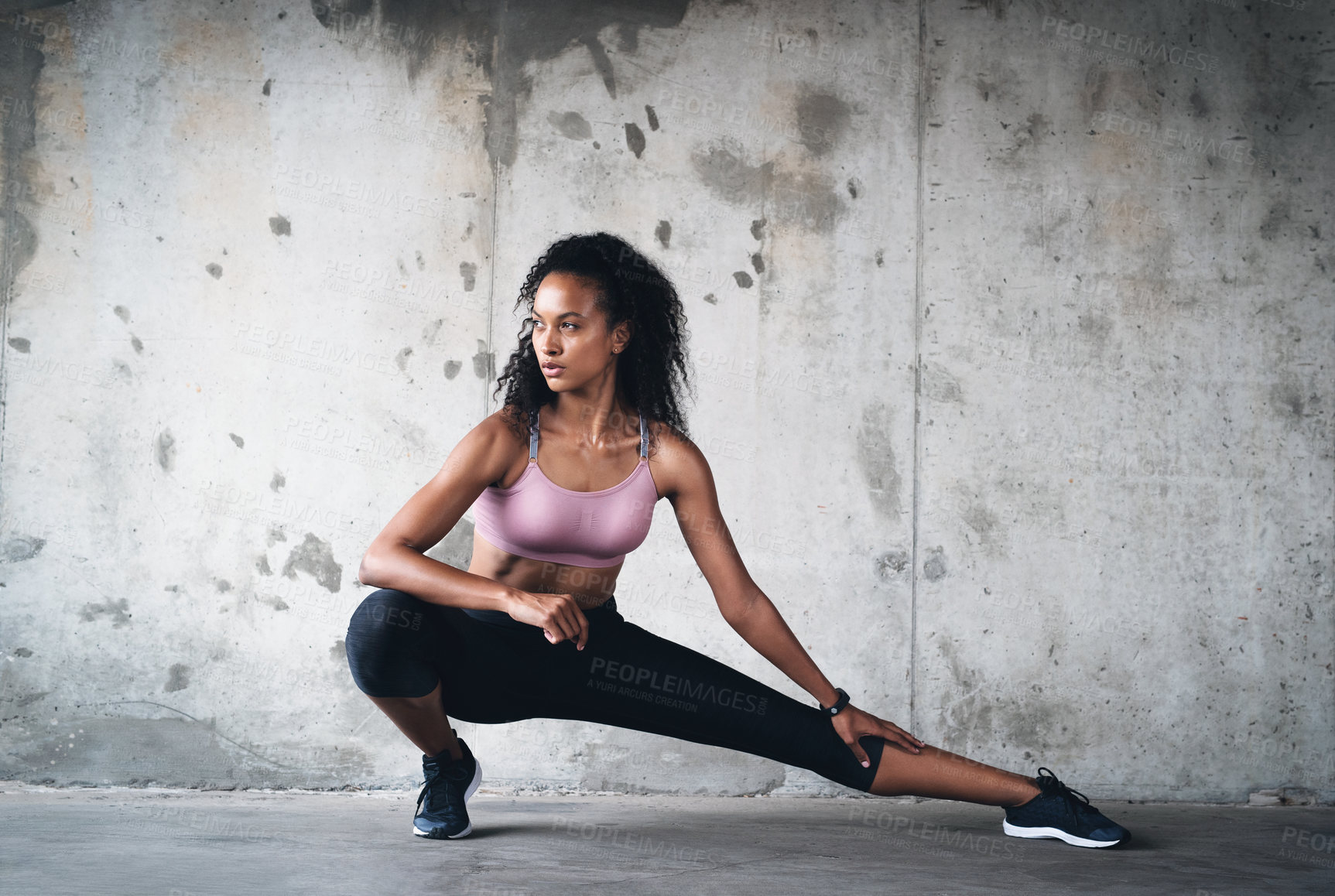 Buy stock photo Full length shot of an attractive young sportswoman stretching while exercising inside a parking lot
