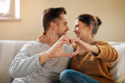 Buy stock photo Shot of a couple forming a heart shape with their hands while sitting together