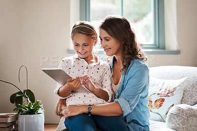 Buy stock photo Shot of an adorable little girl using a digital tablet with her mother at home