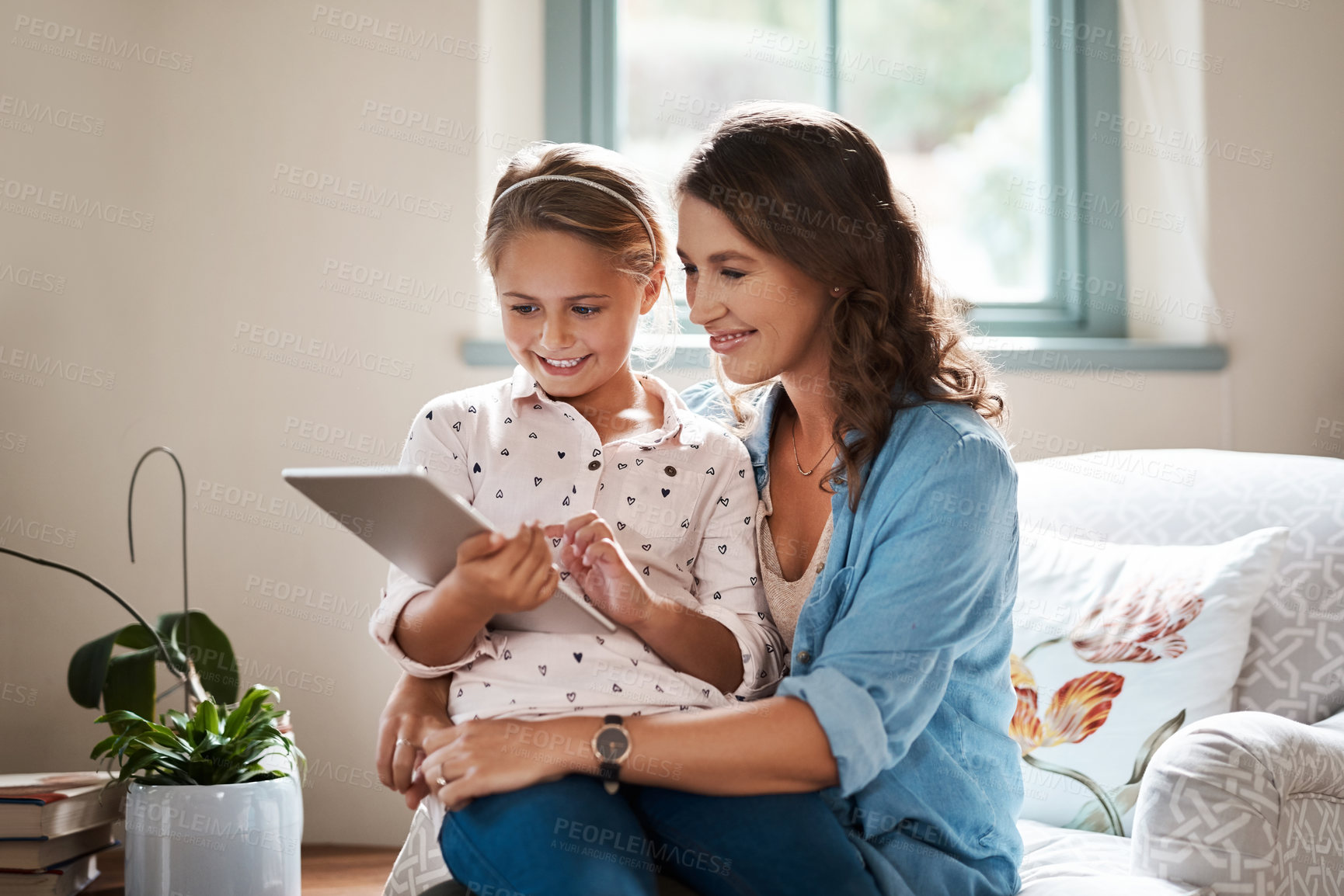 Buy stock photo Shot of an adorable little girl using a digital tablet with her mother at home