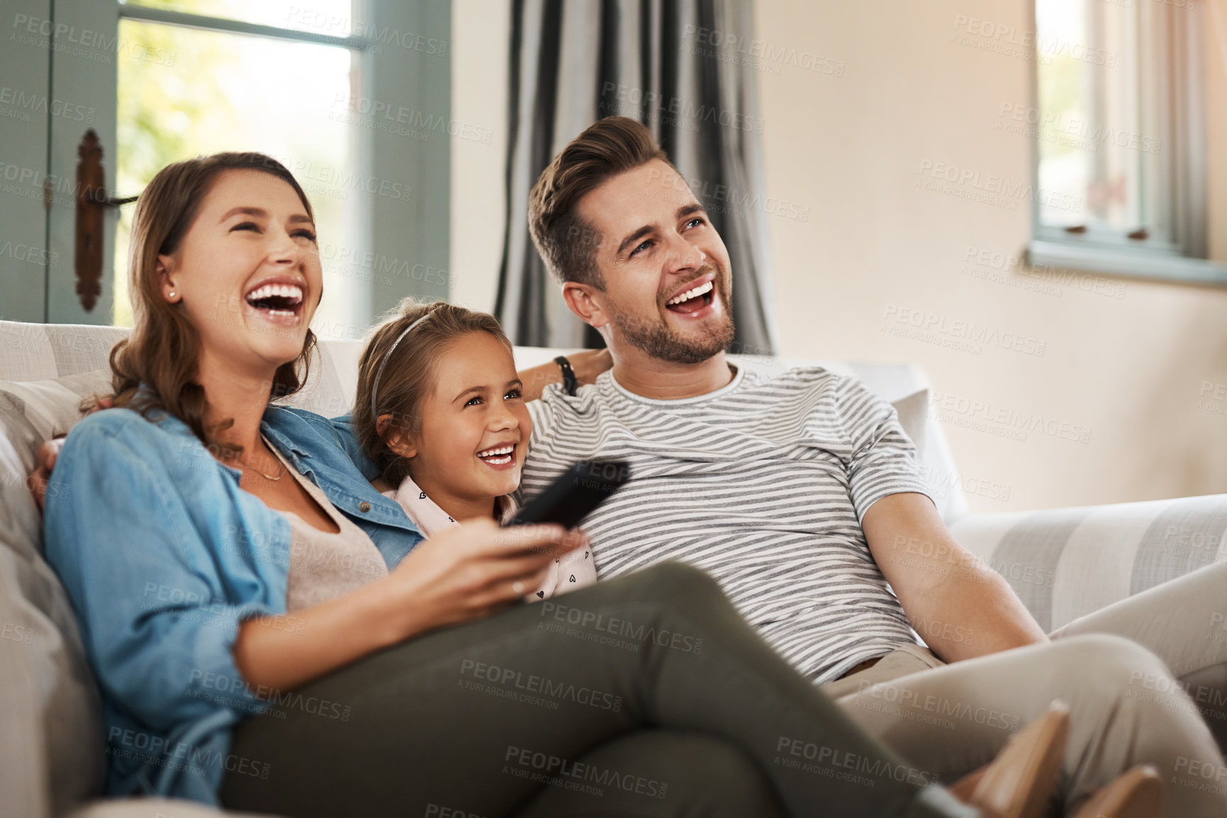 Buy stock photo Parents, girl and watching tv on couch with laugh, remote and relax together for bonding in family house. Father, mother and child with connection, happy and streaming with film, cartoon or movies