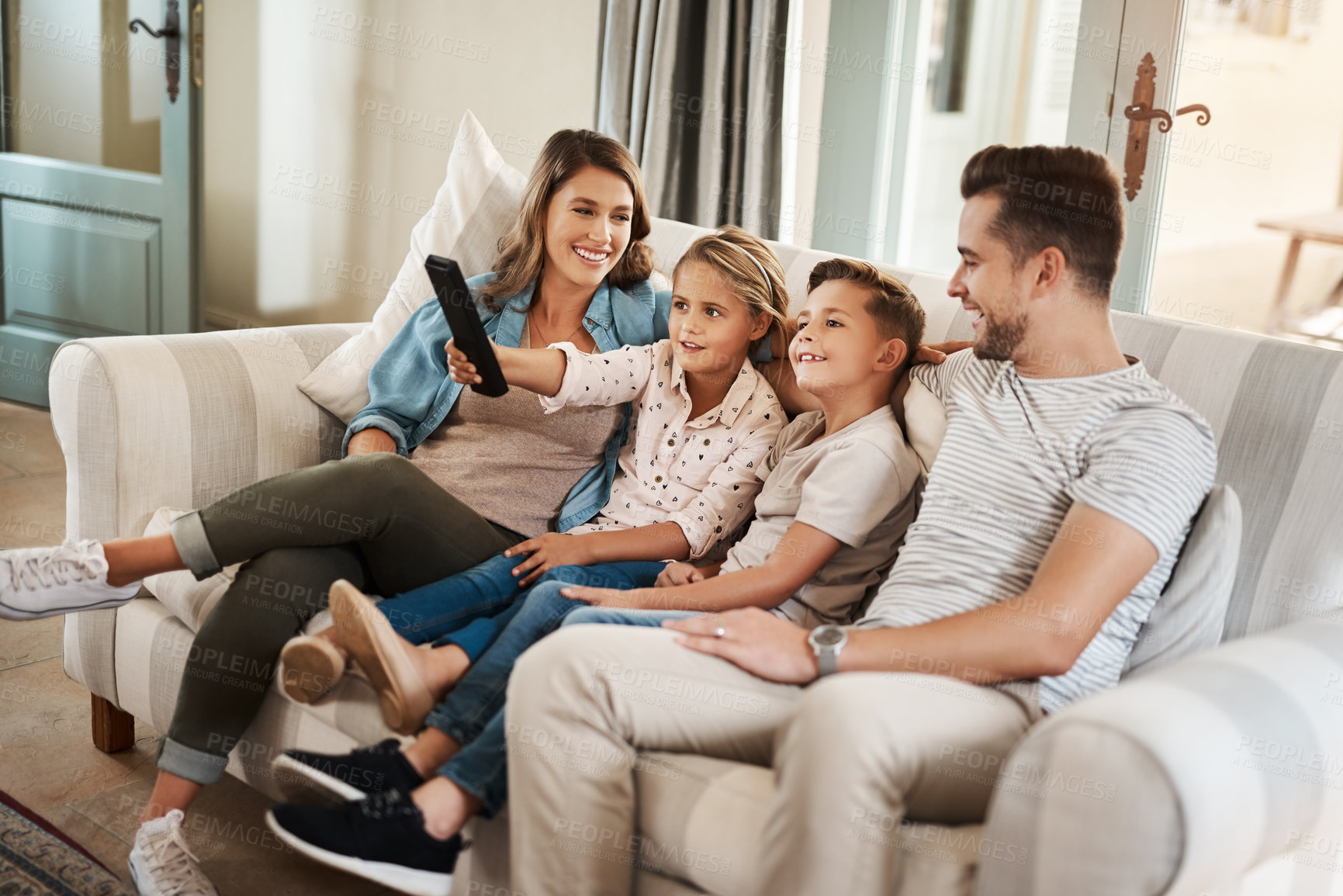 Buy stock photo Parents, kids and watching tv on couch with smile, remote and relax together for bonding in family house. Father, mother and children with connection, happy and streaming with film, cartoon or movies