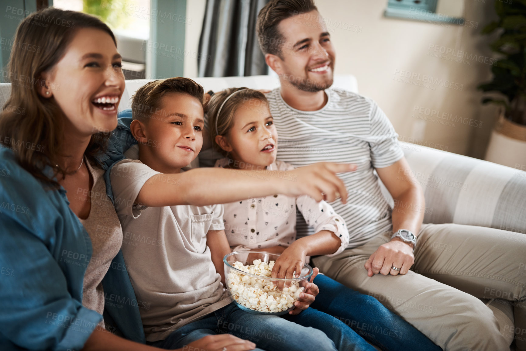 Buy stock photo Shot of a happy young family relaxing on the sofa and watching tv together at home