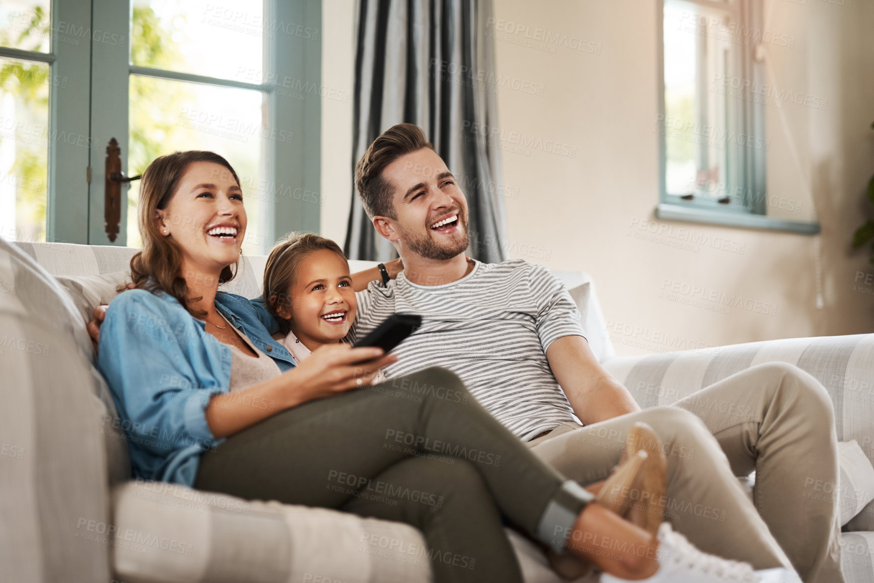 Buy stock photo Shot of a happy young family relaxing on the sofa and watching tv together at home