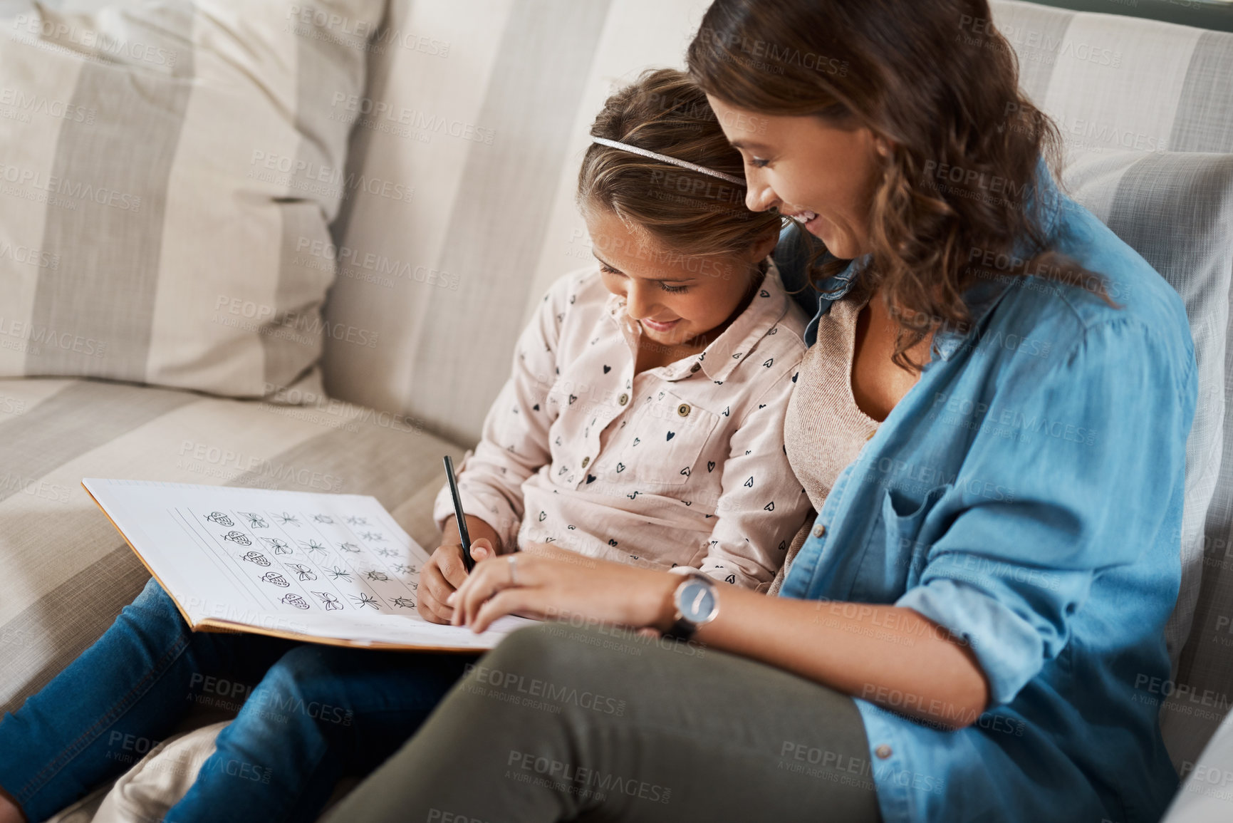Buy stock photo Shot of a young woman helping her adorable daughter with her homework at home