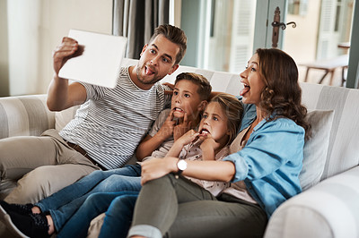 Buy stock photo Shot of a young family of four taking selfies together with a digital tablet on the sofa at home
