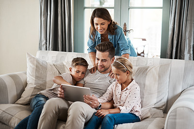 Buy stock photo Shot of a happy young family of four using a digital tablet together on the sofa at home