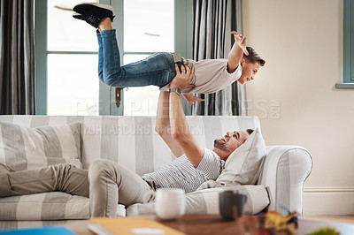 Buy stock photo Shot of an adorable young boy and his father playing together on the sofa at home