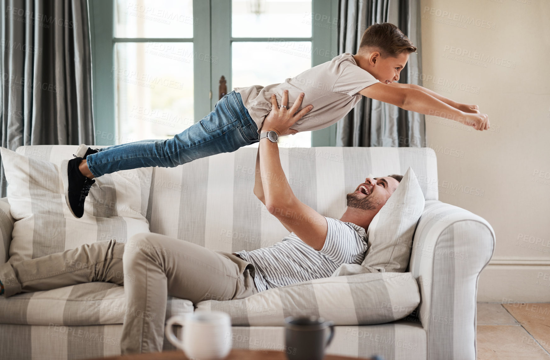 Buy stock photo Shot of an adorable young boy and his father playing together on the sofa at home