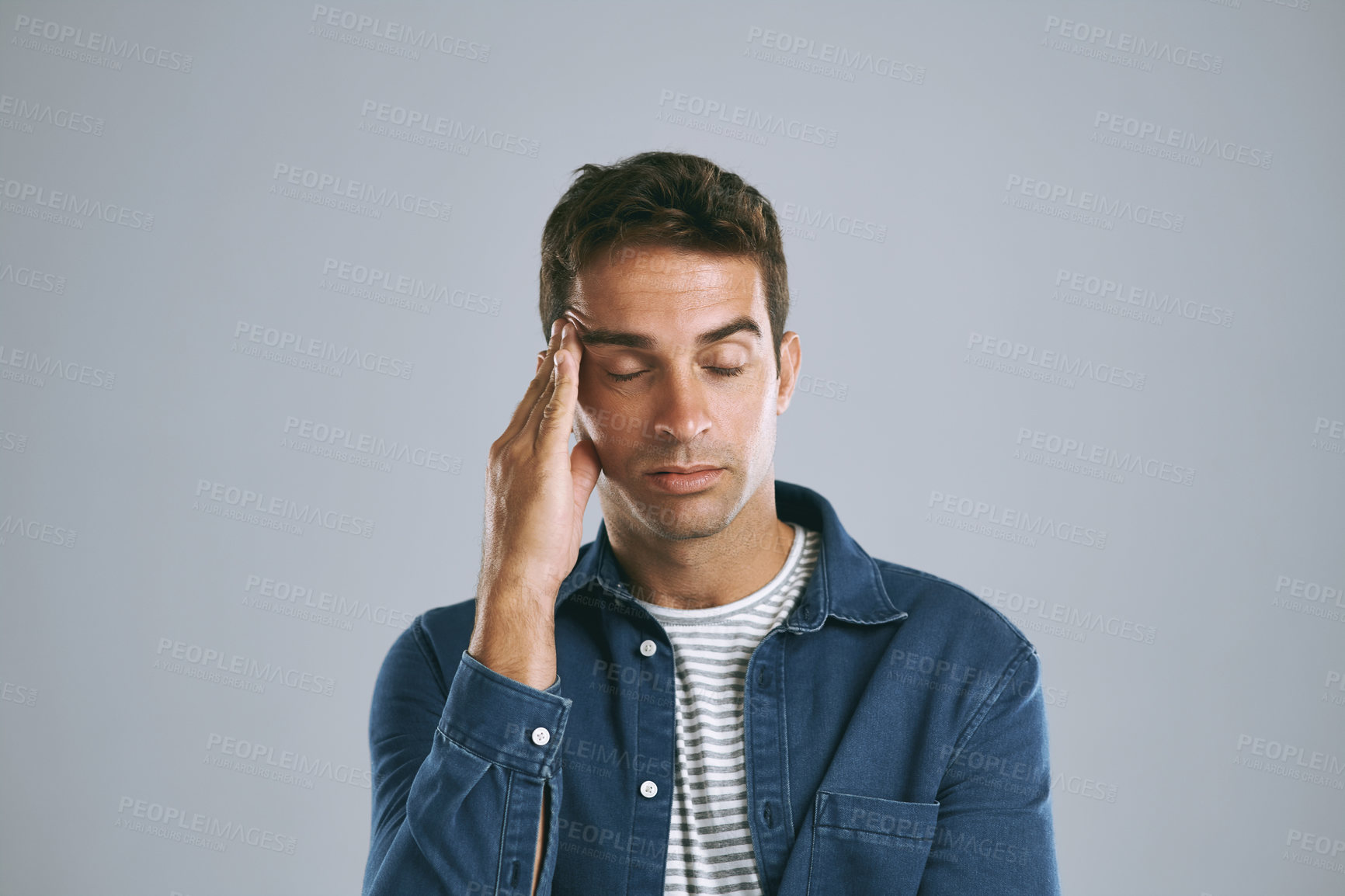 Buy stock photo Cropped shot of a man suffering from a headache against while posing against a grey background