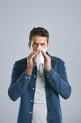 Buy stock photo Cropped shot of a man blowing his nose against a grey background
