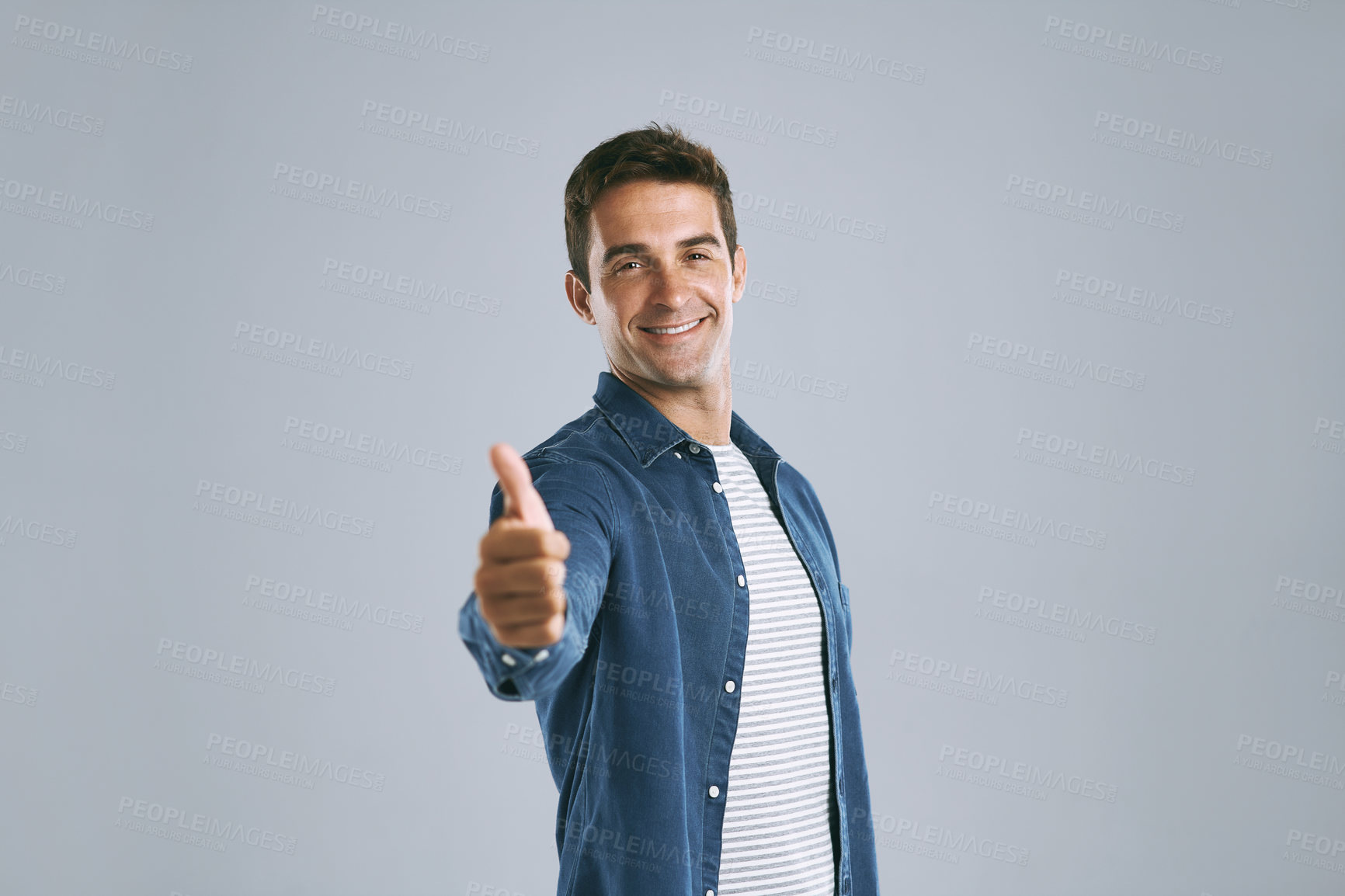 Buy stock photo Cropped shot of a handsome man showing thumbs up against a grey background