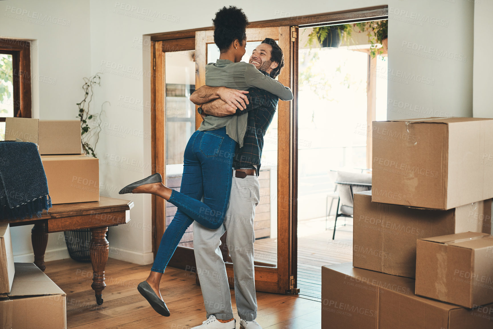 Buy stock photo Happy couple, hug and real estate moving in new home for relocation, renovation or investment together. Interracial man hugging woman and homeowners with boxes in house for move, mortgage or property